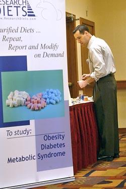 Matthew Ricci, representing Research Diet, which makes custom diets for lab animals so pharmacy companies can test drugs, straightens up his exhibit table at a conference on Metabolic Syndrome in Cambridge, Mass.
