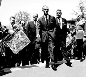 During British Week, his Royal Highness Prince Philip of Great Britain tours the fairgrounds with Ewen Dingwall, behind the prince at left, and Joseph Gandy, right. "Ding," formerly executive director of the Washington State Research Council, was the fair's first paid employee, charged with overseeing the interests of both the city and state, and eventually was named vice president and general manager of Century 21 Exposition, Inc. Exposition President Gandy had cofounded the Smith-Gandy Ford dealership and served as Seattle Chamber of Commerce president in 1956 and 1957.