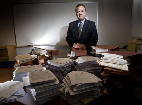 David Hackett, King County prosecutor in charge of civil commitment, stands behind piles of paperwork that represent just slightly more than two cases. 