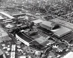 This aerial photo of the World's Fair shows the site of what was once a mostly residential neighborhood that was transformed into Seattle Center. In the foreground, Memorial Stadium is packed with fairgoers attending an event. Across the street is the new parking garage, which remains today, too. 