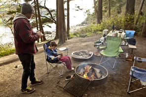 Daniel Braun and his son Oliver Braun, of Seattle, stay warm by the fire at their favorite campsite with a view of the water at Bowman Bay Campground. 