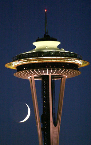  A crescent moon hangs just beneath the observation deck of the Space Needle as twilight fades to night. 