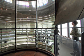 In the park’s interpretive center, a ranger  is framed by the giant Fresnel lens that once magnified the light from the Cape Disappointment lighthouse.