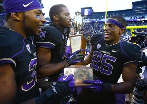 UW’s  Bishop Sankey (25) enjoys the Apple Cup trophy along with  Deontae Cooper, far left, and Kevin Smith, center, after beating Washington State 27-17 Friday.