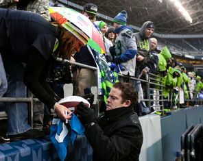 Seahawks general manager John Schneider keeps a low profile, but takes time to sign  autographs for fans.