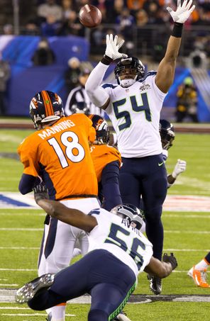 Broncos quarterback Peyton Manning (18) was pressured from the front and the back during the Super Bowl and is shown here lifting a pass over Seahawks linebacker Bobby Wagner (54) in the first half, when Seattle’s defense shut out the high-scoring Denver offense. 