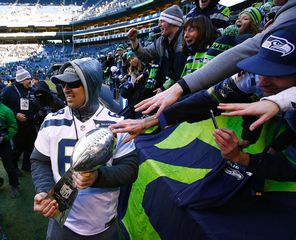 Fans stretch to touch the Lombardi Trophy trotted around by Seahawks player Breno Giacomini.