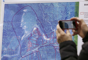 A journalist photographs a map showing the location of Saturday’s deadly mudslide near Oso, Snohomish County. Officials in a Monday news conference said the Stillaguamish River  flooded several buildings upstream from the slide, but that the river had begun cutting a new channel and water levels were starting to subside.