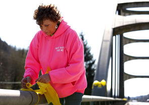 Debra Hoskins, a church pastor, ties yellow ribbons Tuesday onto a bridge crossing the North Fork of the Stillaguamish River, down the road from the   slide. “Ribbons signify that you expect the return of a loved one,” she said. 