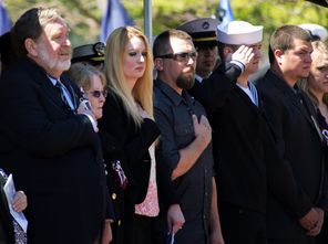 Family members of Cmdr. Regelbrugge stand as the national anthem plays at the memorial service at Naval Station Everett on Friday.