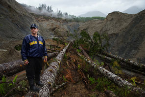 John Reed, who lives at the edge of the Oso mudslide, stands in the debris field on the bank of the North Fork Stillaguamish River recently. 